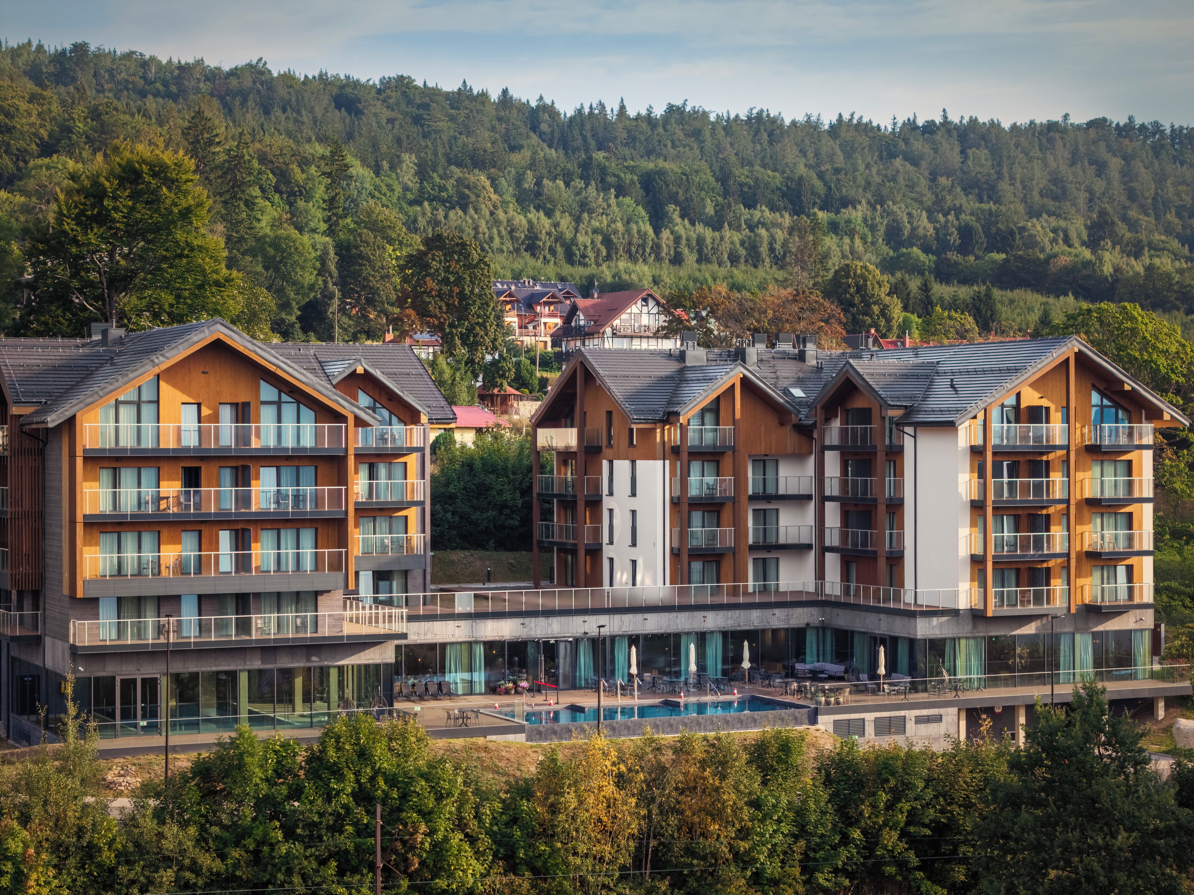 Un hotel moderno con varios pisos, balcones y una piscina.