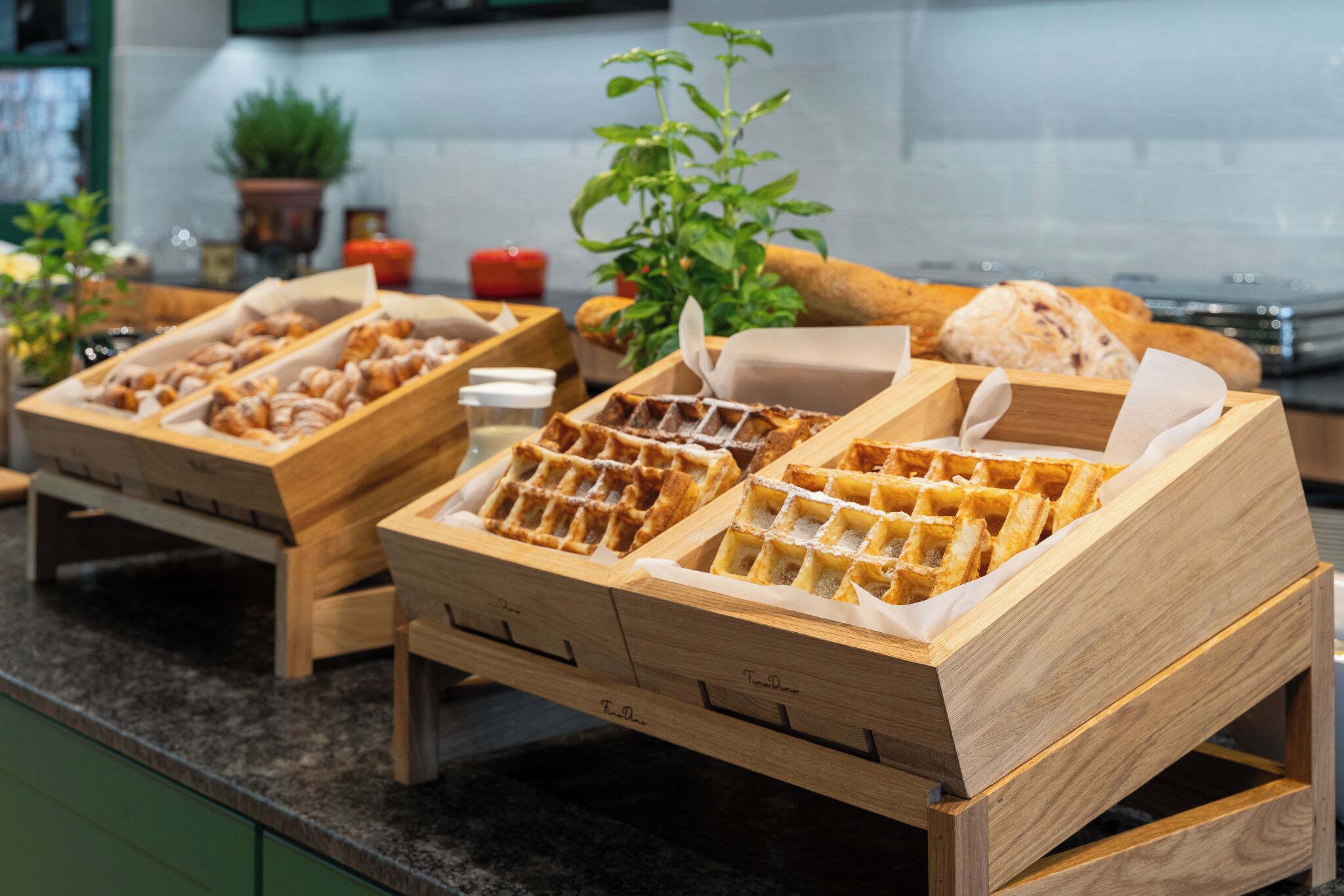 Una encimera de cocina con máquinas para hacer gofres de madera y una planta en maceta.