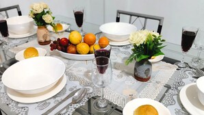 Une table à manger dressée avec de l’assiette blanche, des bols et un vase rempli de fleurs.