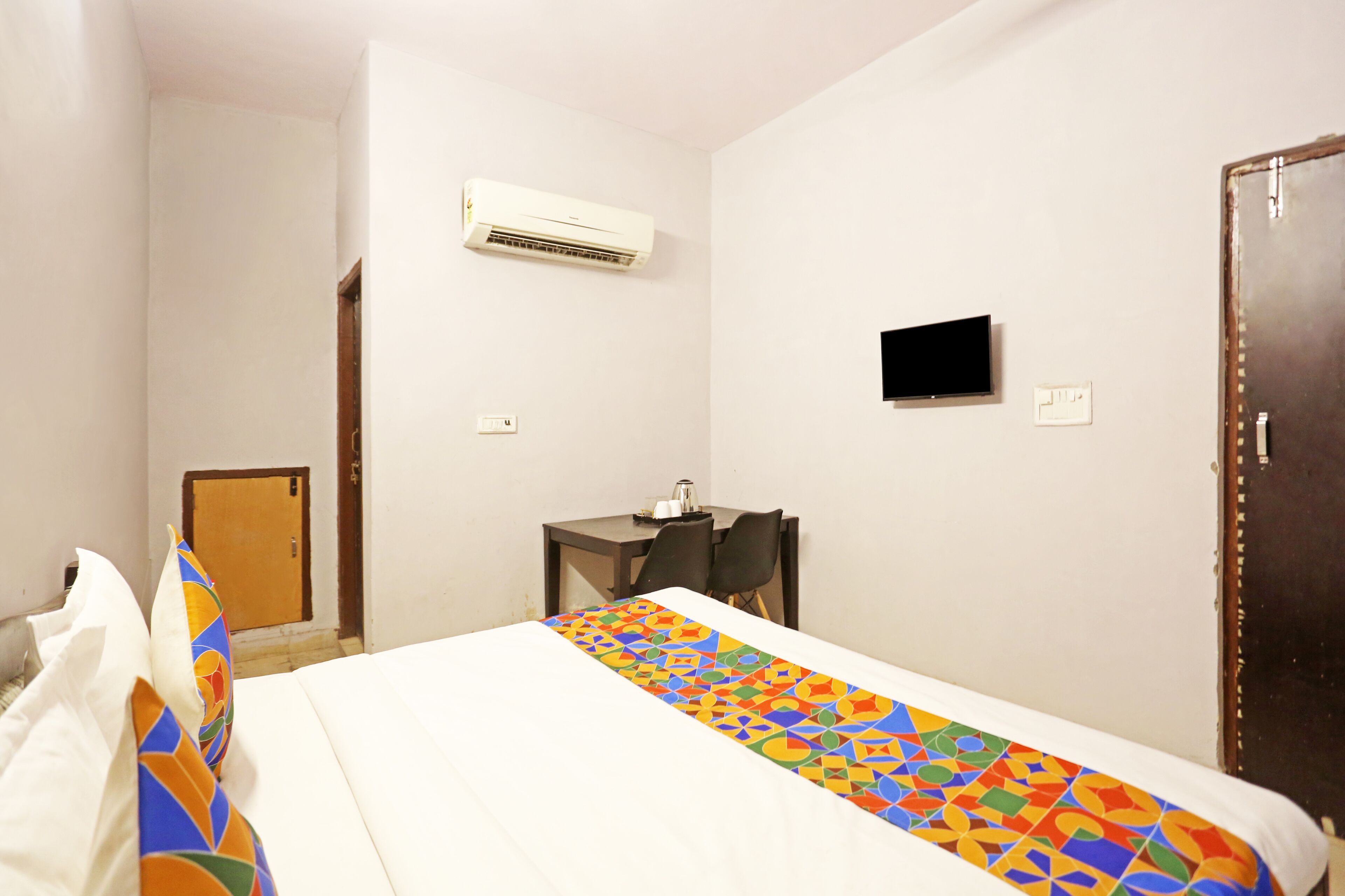 Una habitación de hotel con cama, escritorio, aire acondicionado, televisor y puerta.