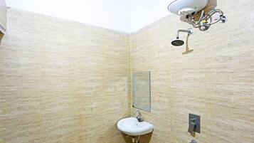 A bathroom with a beige tiled wall, a white sink, a mirror, and a shower head.