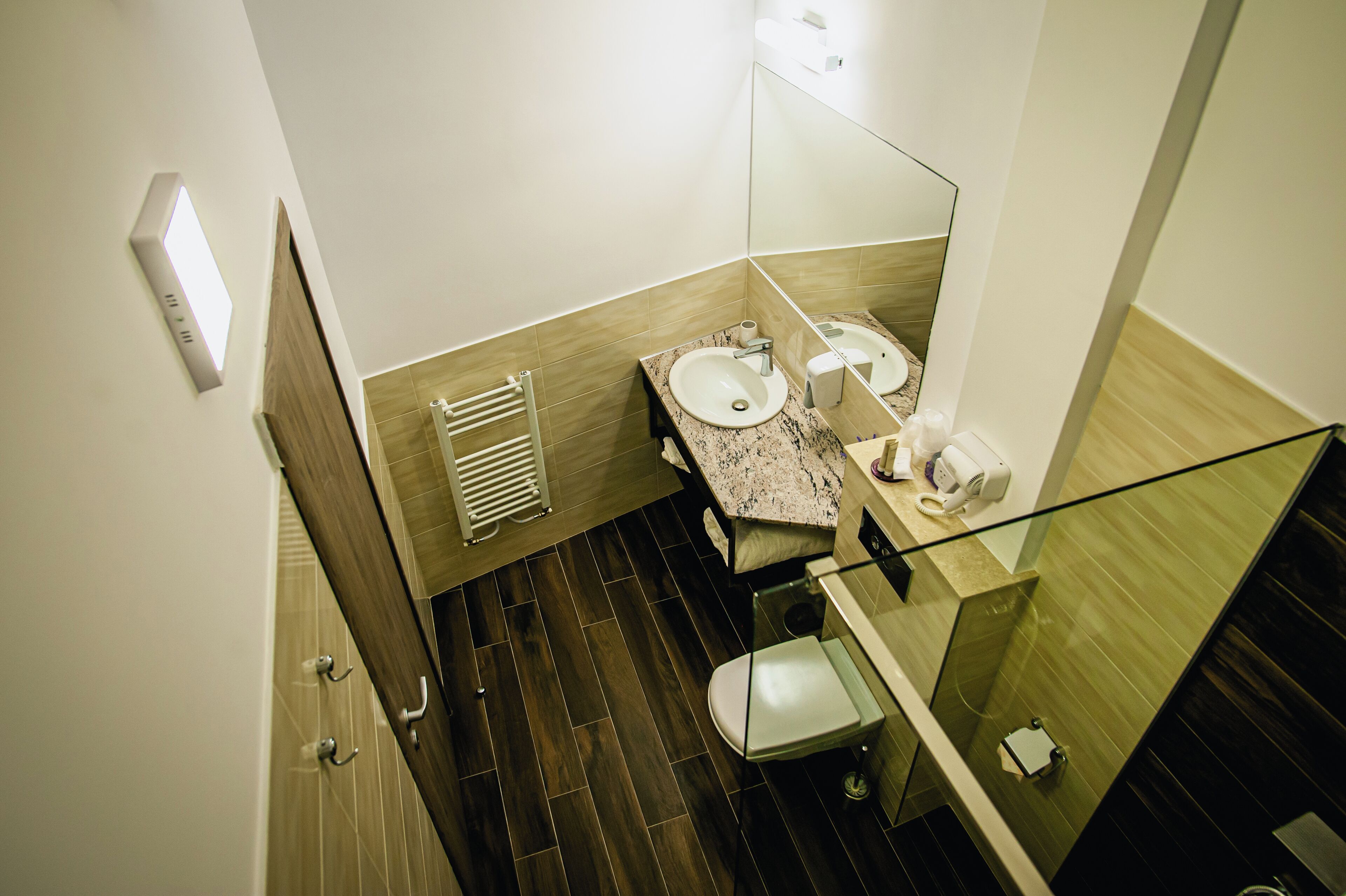 A modern bathroom with two sinks, a glass shower enclosure, and a wooden floor.