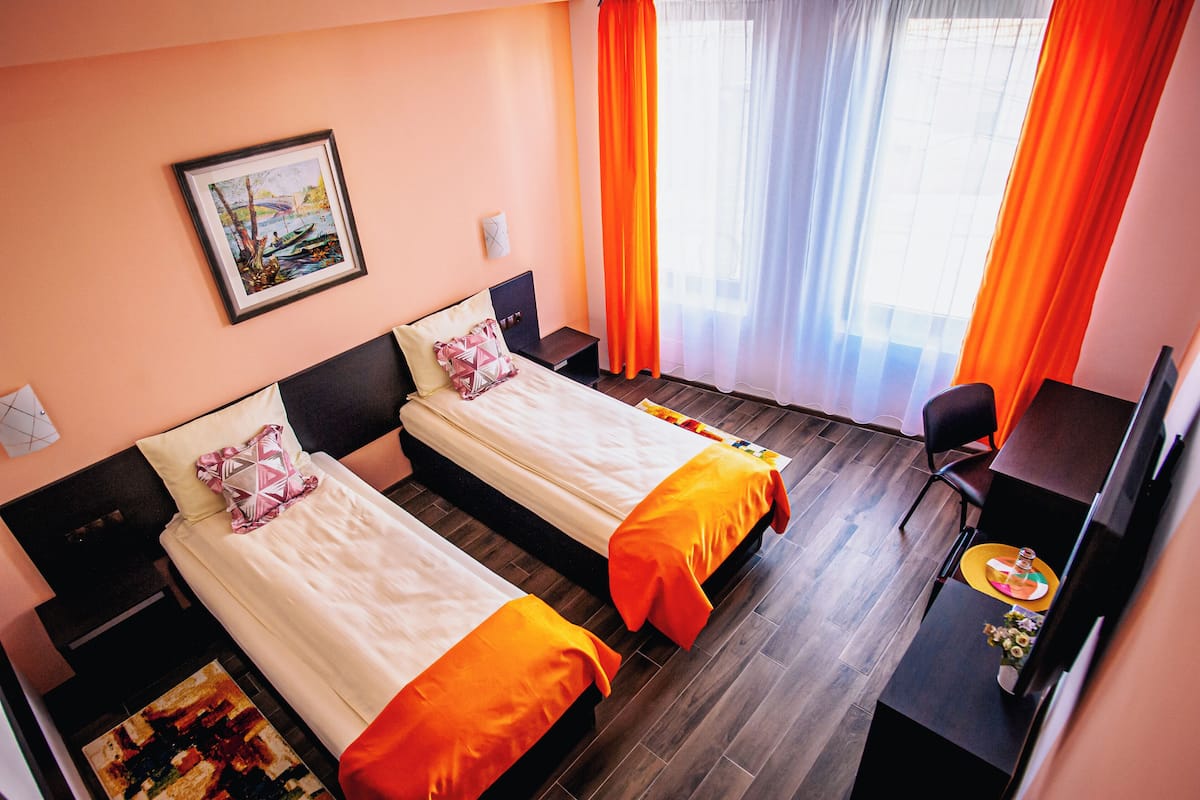 A hotel room with two beds, a desk, and a chair.