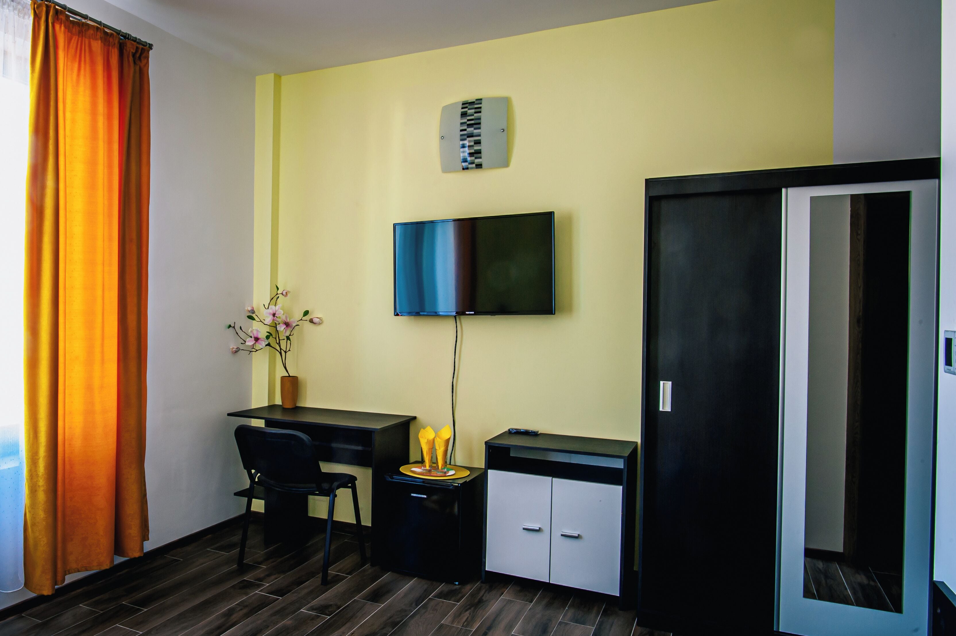 A room with a desk, chair, TV, cabinet, and a door.