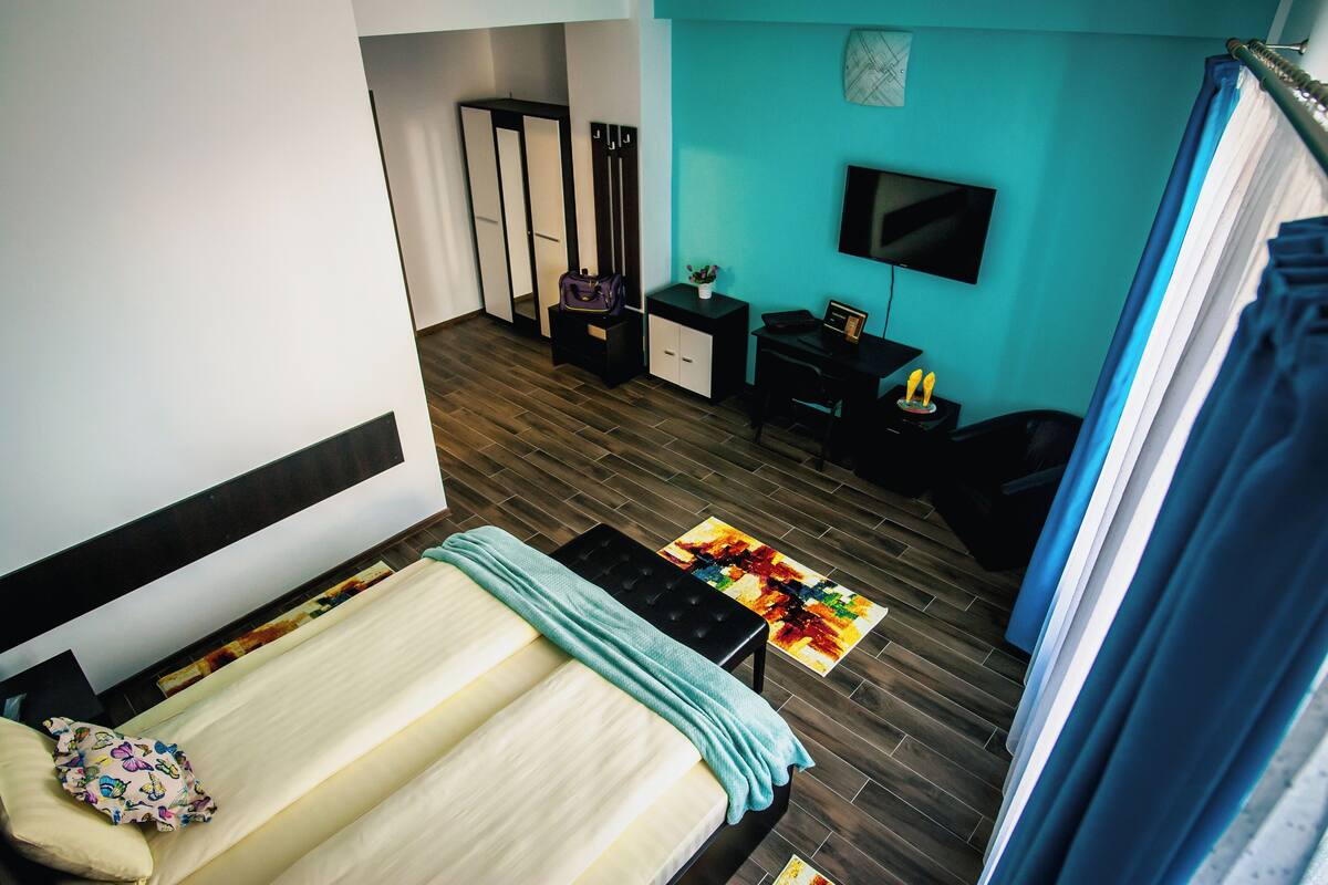 A bedroom with a bed, a desk, a chair, a TV, and a wardrobe.