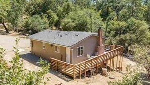A single-story house with a fenced deck, surrounded by trees. - Mountain View, Near Yosemite & Bass Lake, EVC, BBQ (Oakhurst)