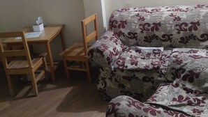 A small room with a wooden desk, a chair, and a patterned sofa. - Hotel Harmony Bistro (Lalitpur)