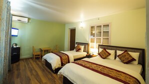 A hotel room with two beds, a desk, a chair, and an air conditioning unit. - Hotel Harmony Bistro (Lalitpur)