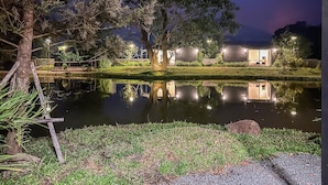 A nighttime view of a hotel with a reflective pond, trees, and outdoor lighting. - Na Muen See  (Samoeng)