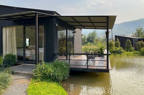 Una casa moderna con puerta de vidrio, zona exterior cubierta y un estanque.