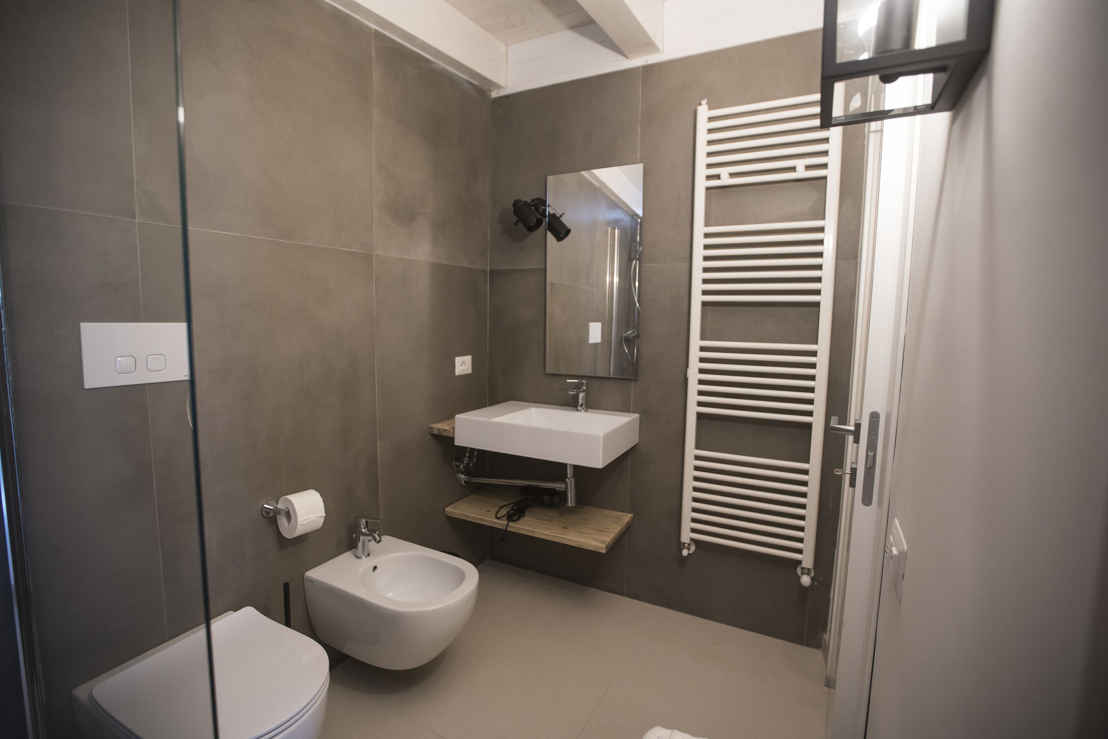 Ein modernes Badezimmer mit Toilette, Bidet, Waschbecken und Handtuchhalter.
