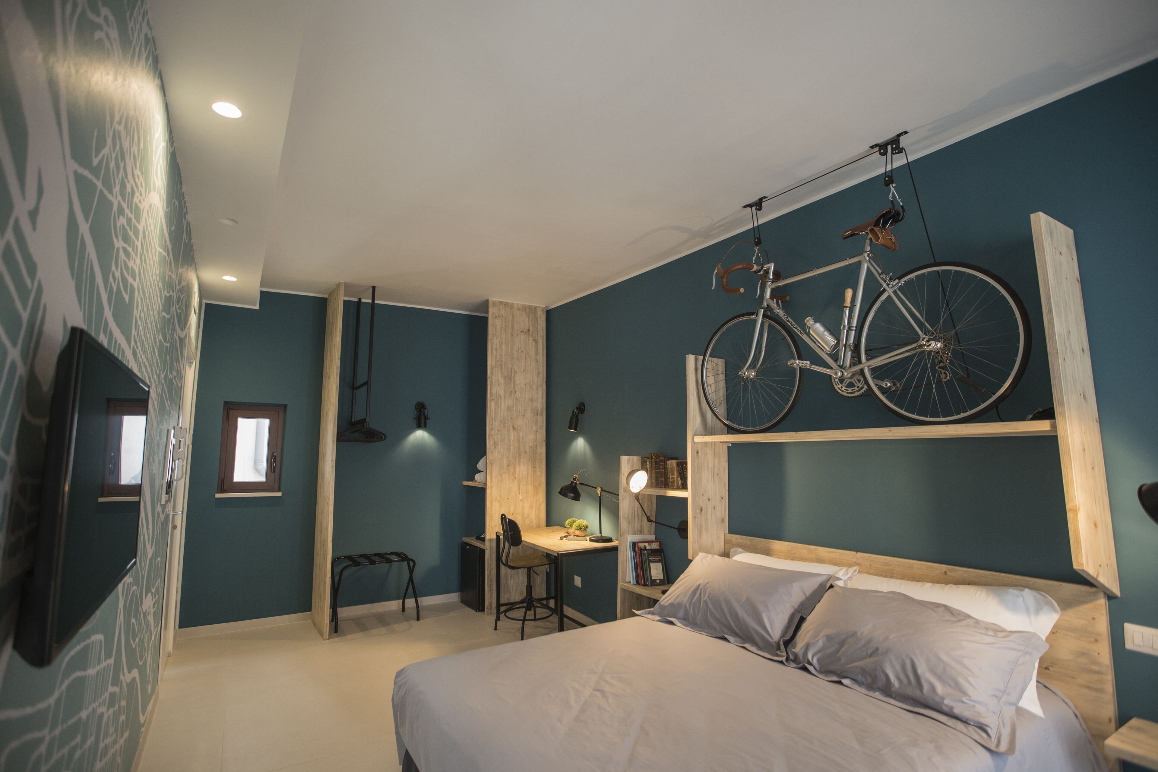 A bedroom with a bed, a desk, and a bicycle mounted on the wall.