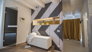 Une pièce moderne avec un canapé blanc, un miroir et un mur orné d’un motif géométrique.