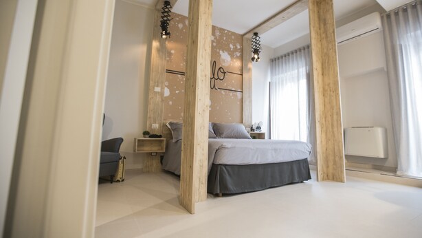 Une chambre moderne avec un grand lit, des poutres en bois, un bureau et une chaise.