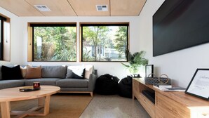Una sala de estar moderna con un sofá gris, una mesa de centro de madera y un escritorio con una computadora y un letrero de bienvenida enmarcado.