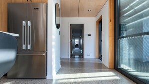 Una cocina moderna con electrodomésticos de acero inoxidable, una encimera de madera y un pasillo que conduce a una puerta.