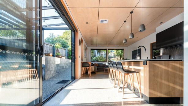 Una cocina moderna con barra, ventanas amplias y una zona de estar con sofá y sillones.