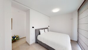 Ein Schlafzimmer mit einem Bett, einem Nachttisch, einer Wandleuchte und einer Blumenkomposition.