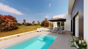 Ein moderner Poolbereich im Freien mit Liegestühlen und einer überdachten Sitzgelegenheit.