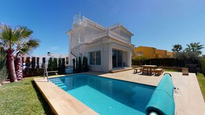 Una casa moderna con piscina, un porche cubierto y una escalera de caracol.