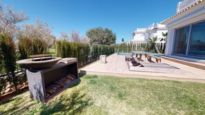 A modern outdoor patio with a fire pit, a pool table, and a wooden deck. - Greenside oasis villa by ON Travel (Oliva)