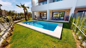 A modern residential property with a swimming pool, outdoor seating area, and a view of the surrounding neighborhood. - Los Lagos by ON Travel (Oliva)