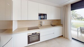 Una cocina moderna con armarios blancos, un lavamanos de acero inoxidable y un horno.