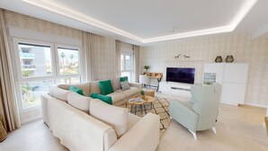 Un salon moderne avec un canapé, un fauteuil, une télévision et une petite table.