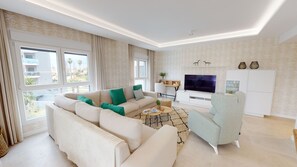 A modern living room with a sectional sofa, a coffee table, a TV, and a seating area with a chair.