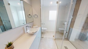 Een moderne badkamer met een douchecabine van glas, een wit wastafelmeubel en een spiegel.