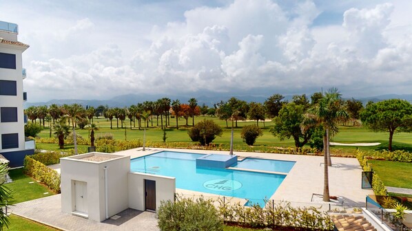 A pool with a view of a golf course and mountains.
