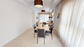 Een moderne eetruimte met een houten tafel, zwarte stoelen en een groot raam met gordijnen.