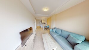 Una sala de estar moderna con sofá, televisor y comedor con sillas y mesa.