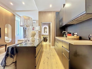 Une cuisine moderne dotée d’appareils électroménagers en acier inoxydable, d’un îlot central avec un plan de travail en verre et d’un plancher en bois.