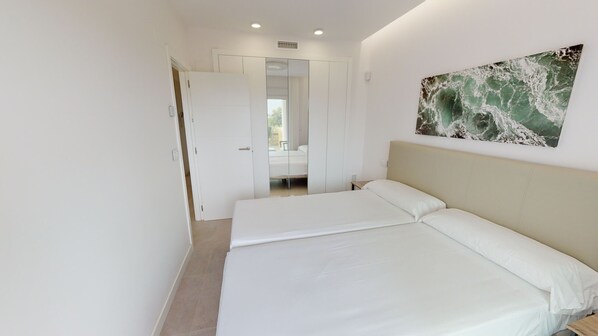 A bedroom with a bed, a door leading to a bathroom, and a wall-mounted artwork.