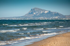 A beach with waves and a mountain in the background.