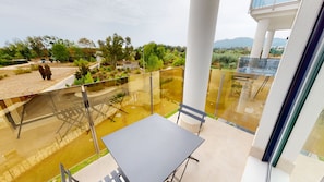 A balcony with a glass barrier, a table, and chairs. - Prímula by ON Travel (Oliva)