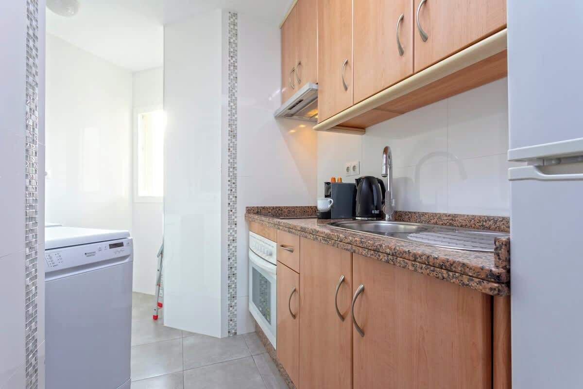 A compact kitchen with wooden cabinets, a granite countertop, a built-in oven, and a dishwasher.