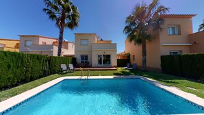 A swimming pool with a clear blue water, surrounded by a well-maintained lawn and palm trees. - Gloire by ON Travel (Oliva)