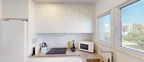 A modern kitchen with white cabinets, a stainless steel sink, a microwave, and a toaster.