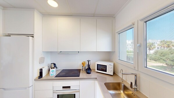 A modern kitchen with white cabinets, a stainless steel sink, a microwave, and a toaster.