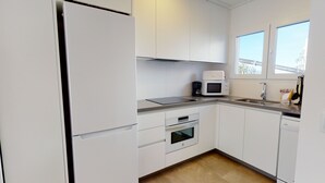 A modern kitchen with white cabinets, a built-in oven, a microwave, and a coffee maker. - Nobilis by ON Travel (Oliva)