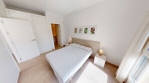 Ein Schlafzimmer mit Bett, Nachttischen, einem Kleiderschrank und einer Tür.