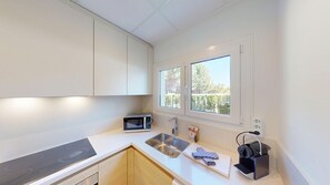 Eine moderne Küche mit eingebauter Mikrowelle, Spüle aus Edelstahl und einem Fenster mit Blick auf Bäume.