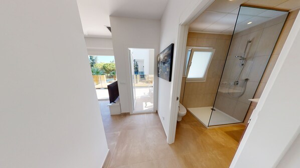 A modern bathroom with a glass shower enclosure, a toilet, and a sink.