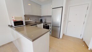 A modern kitchen with a central island, stainless steel appliances, and a white color scheme.