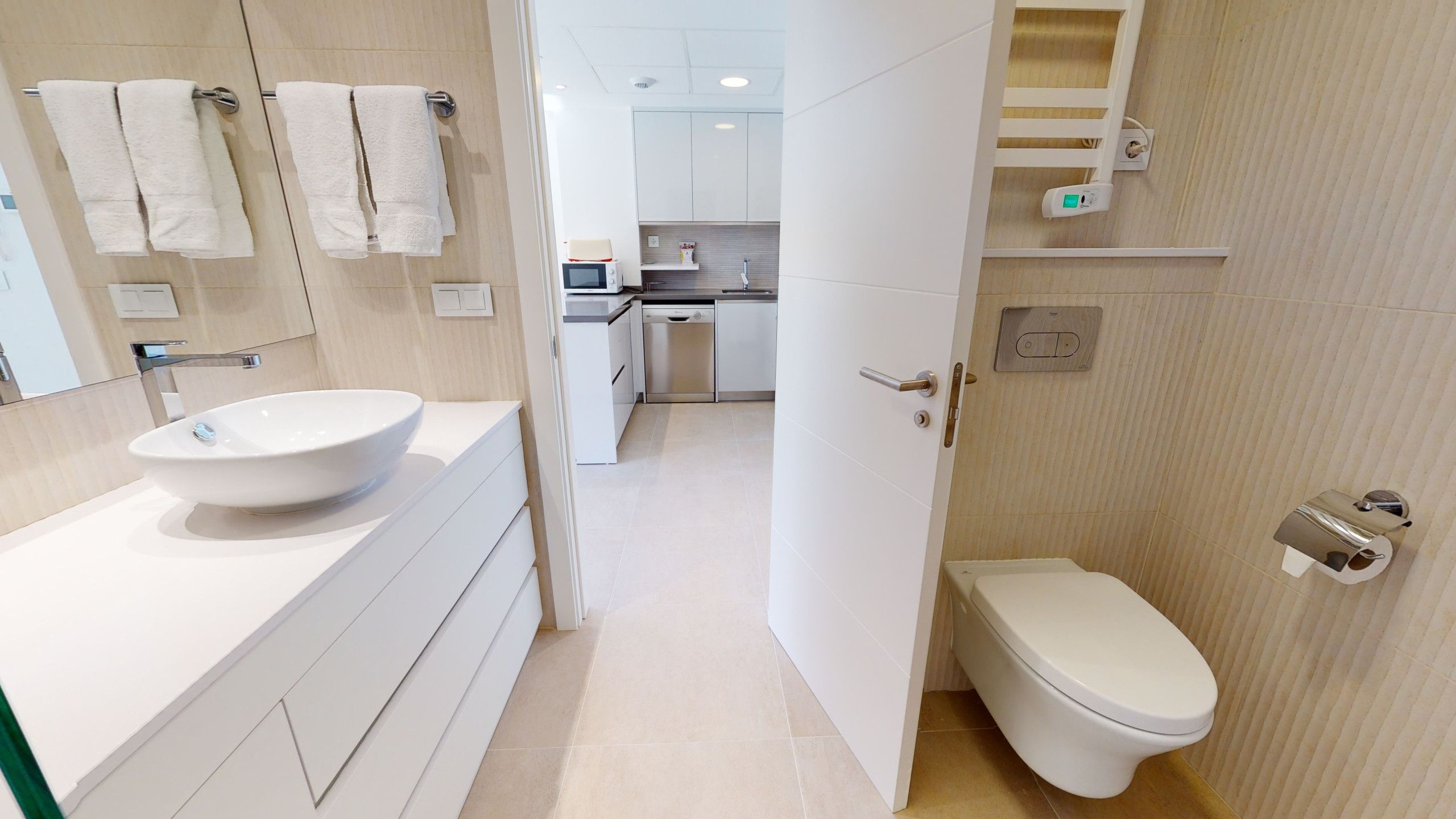 Un baño moderno con lavamanos, inodoro y espejo blancos.