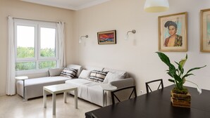 Een woonkamer met een bank, een eettafel en een potplant.