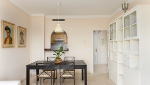 Een eethoek met een tafel, stoelen, een hanglamp en een witte kast.