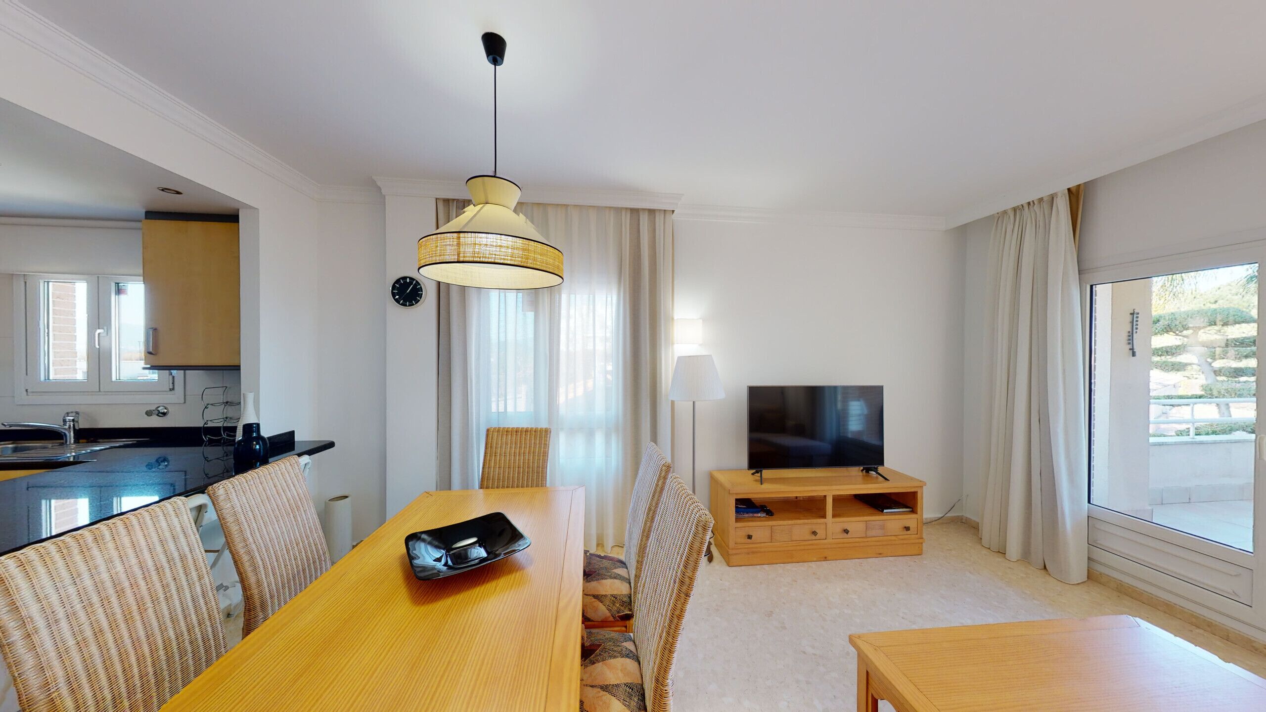 A modern hotel room with a dining area, a TV, and a view of the outdoors.